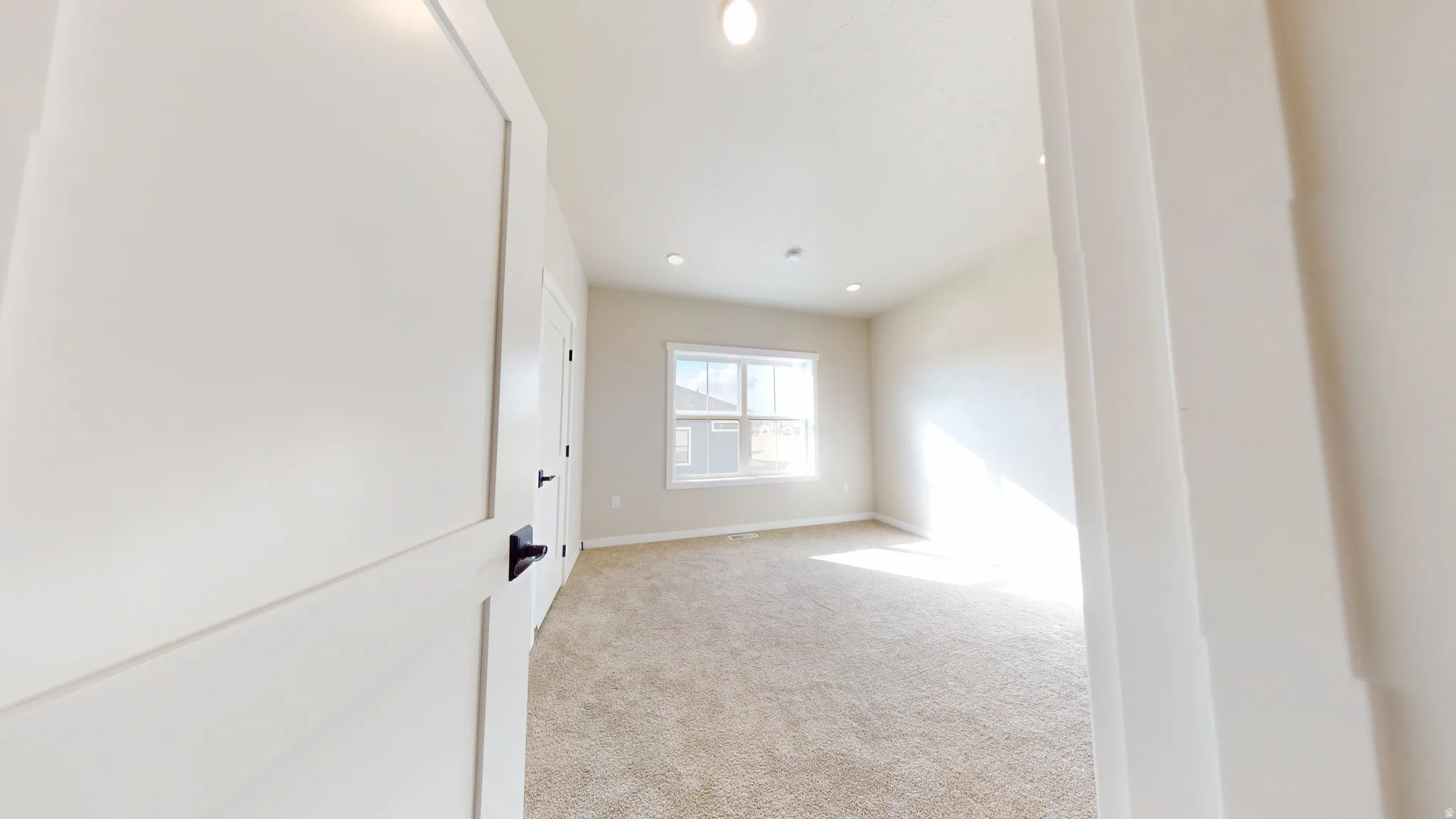 Empty room with light carpet and recessed lighting