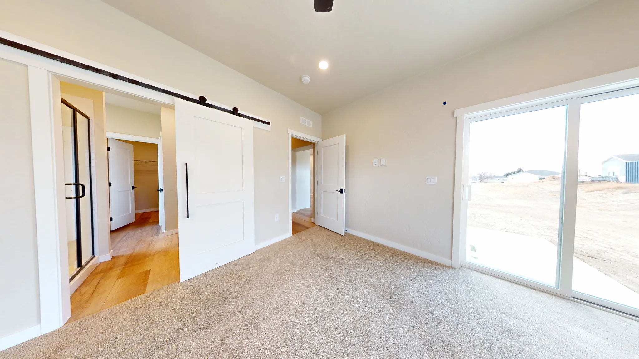 Unfurnished bedroom with a barn door, access to exterior, light carpet, recessed lighting, and a ceiling fan