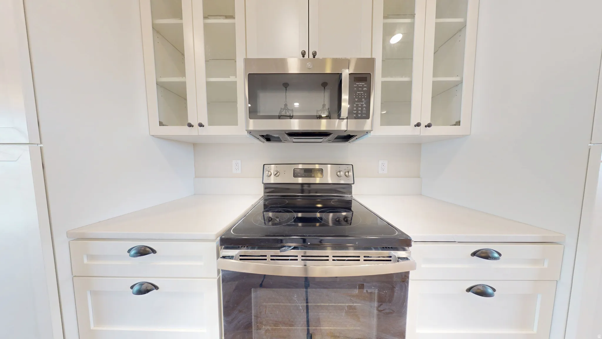 Kitchen featuring appliances with stainless steel finishes, white cabinetry, and glass insert cabinets
