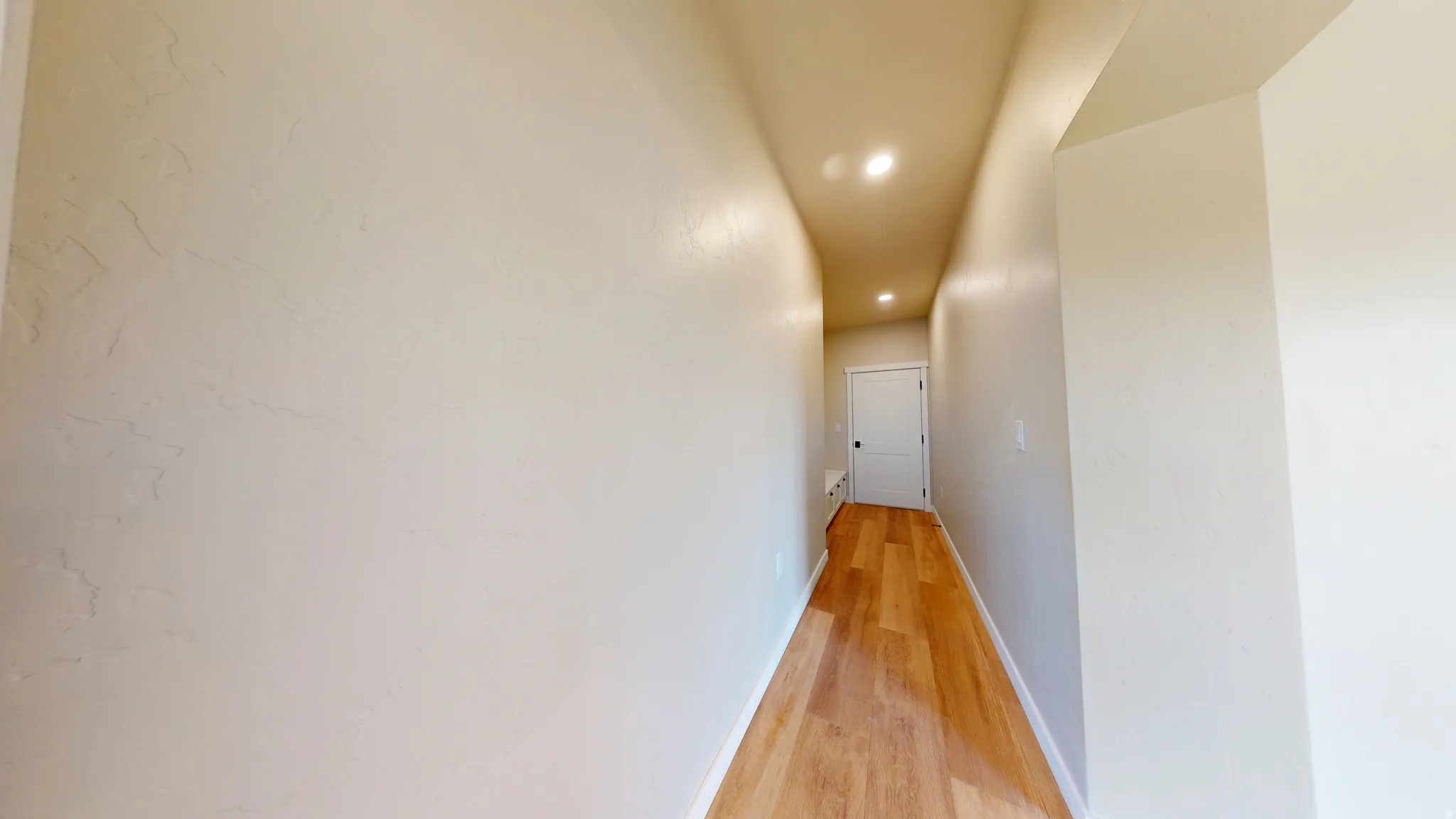 Hall with light wood-style floors and recessed lighting