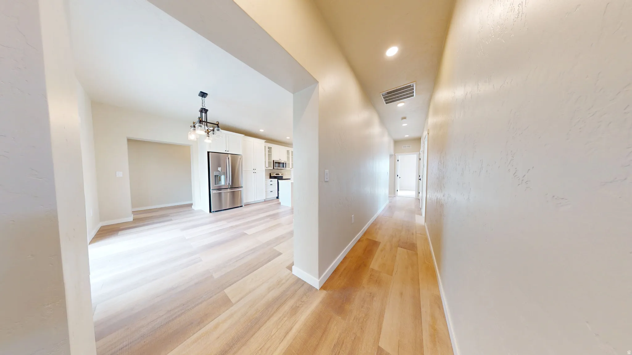 Corridor with recessed lighting, light wood-style floors, and a chandelier