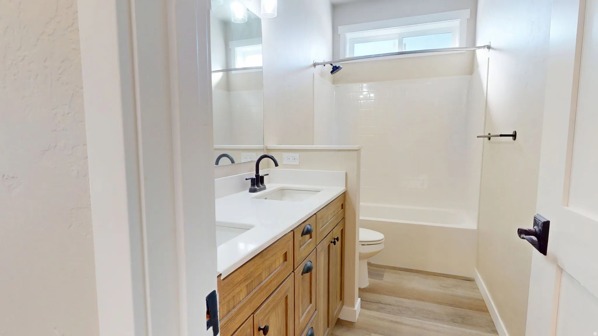Full bathroom with double vanity, light wood-type flooring, and shower / bathtub combination