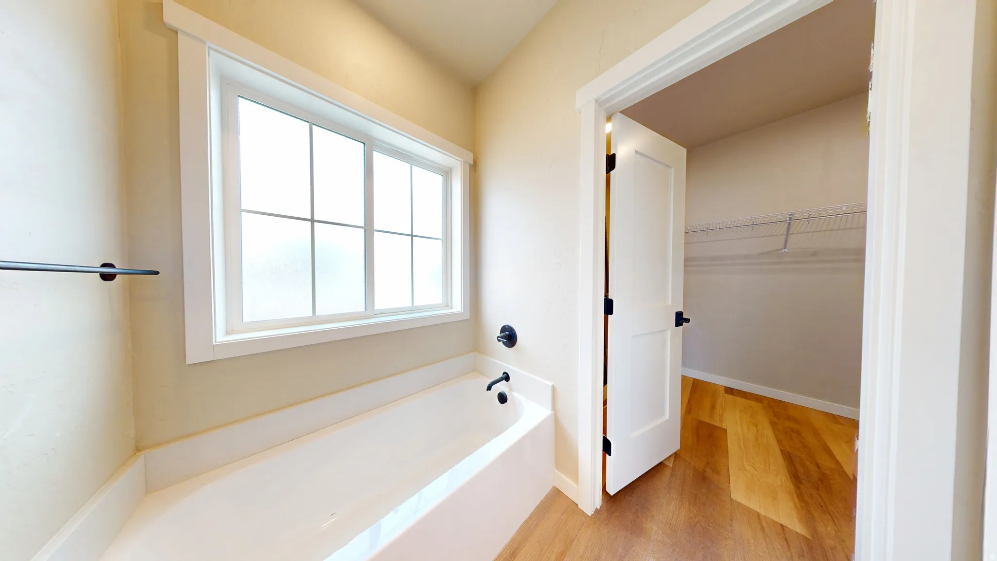 Full bathroom with a bath, light wood-type flooring, and a walk in closet
