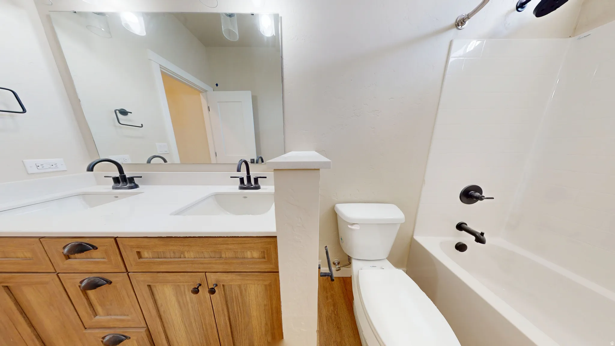 Bathroom featuring double vanity, bathing tub / shower combination, and light wood-type flooring