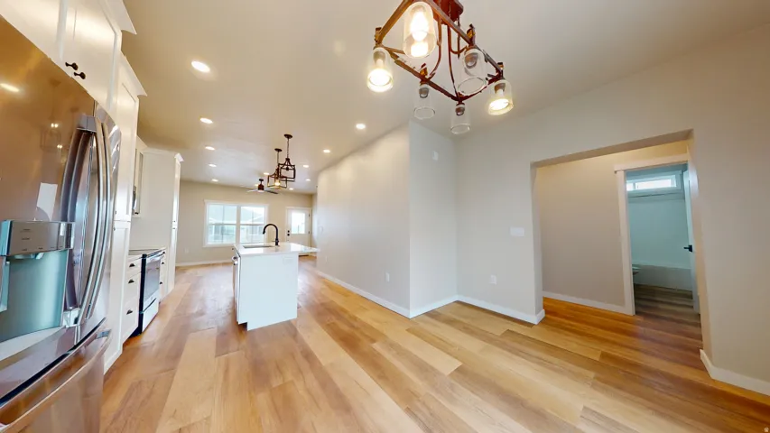Kitchen with stainless steel appliances, white cabinetry, hanging light fixtures, recessed lighting, and a kitchen island with sink