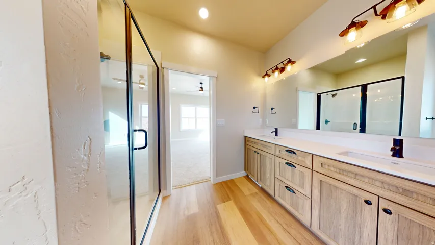 Full bathroom with double vanity, light wood finished floors, a shower stall, recessed lighting, and a ceiling fan