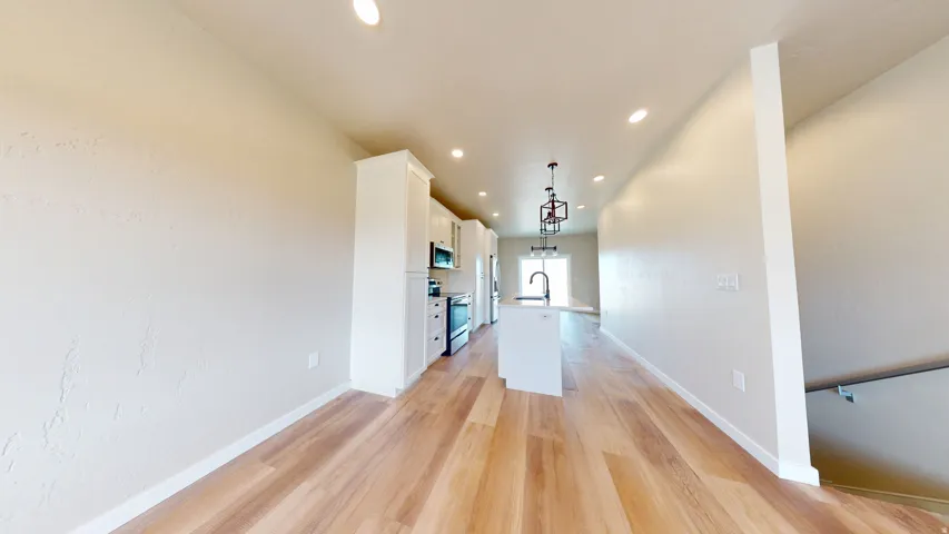 Kitchen featuring white cabinets, a kitchen island with sink, light wood-style floors, decorative light fixtures, and recessed lighting