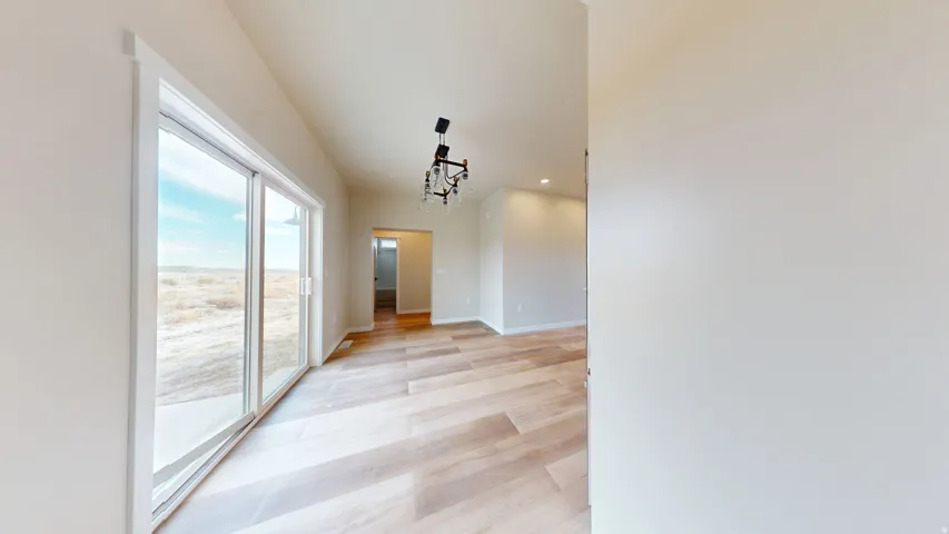 Corridor featuring light wood finished floors, recessed lighting, and a chandelier