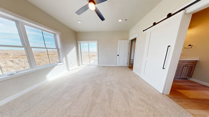 Unfurnished bedroom with a barn door, access to outside, light carpet, a ceiling fan, and recessed lighting