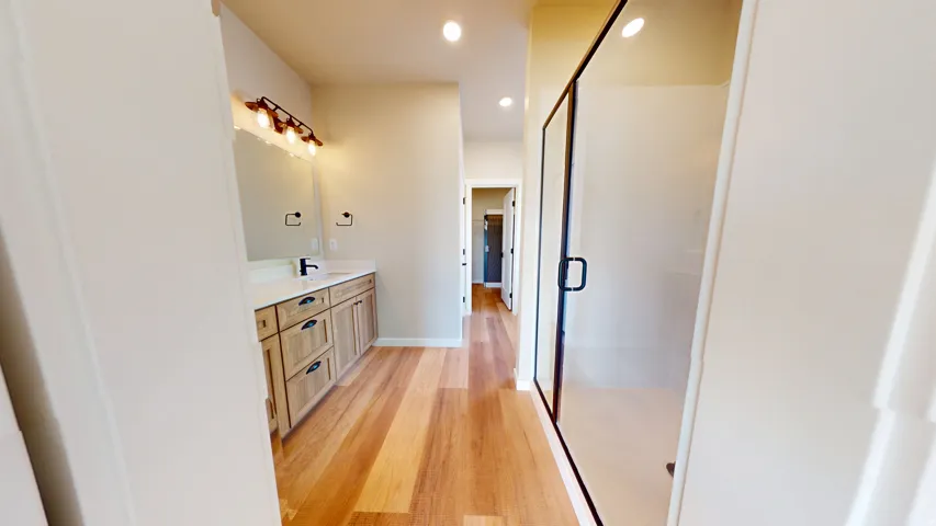Bathroom with light wood-style flooring, recessed lighting, vanity, and a shower stall
