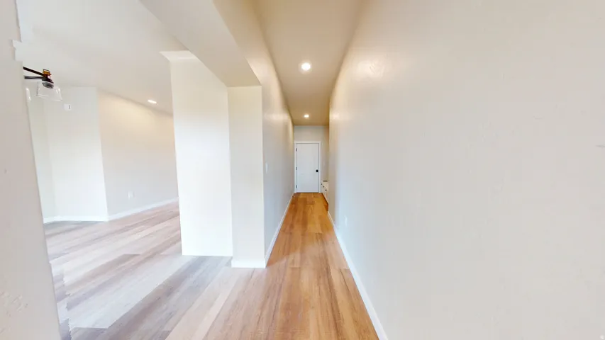 Corridor with light wood-style floors and recessed lighting