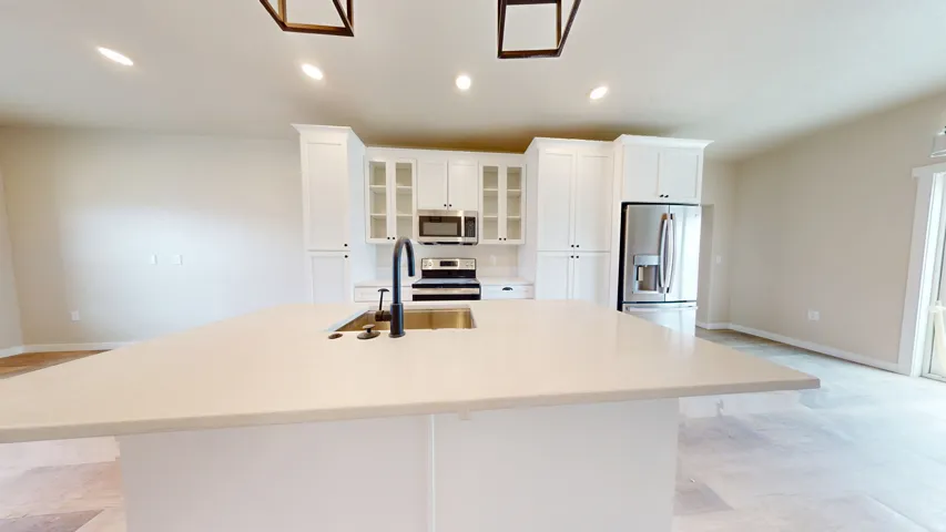 Kitchen featuring recessed lighting, glass insert cabinets, appliances with stainless steel finishes, white cabinetry, and a kitchen island with sink