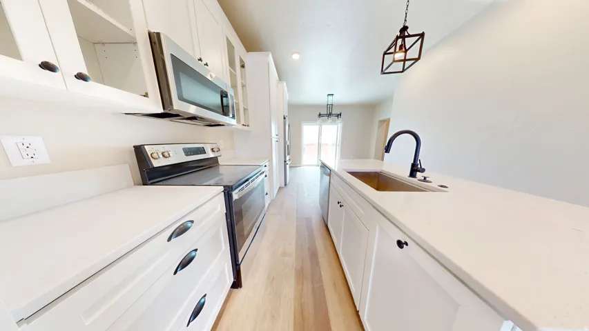 Kitchen with white cabinetry, stainless steel appliances, light wood-style flooring, pendant lighting, and glass insert cabinets