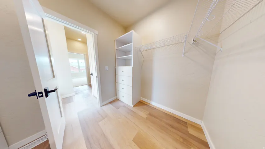 Spacious closet featuring light wood-style flooring