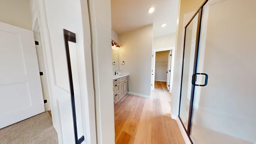 Hallway with light wood-type flooring and recessed lighting