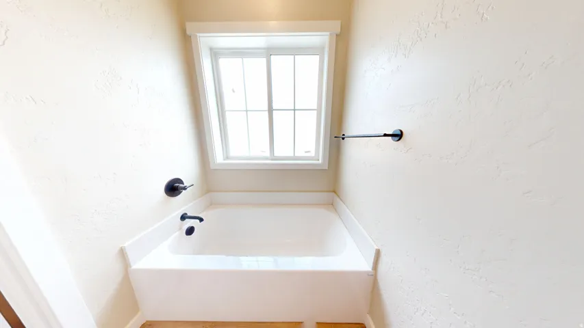 Full bathroom with a textured wall and a bath