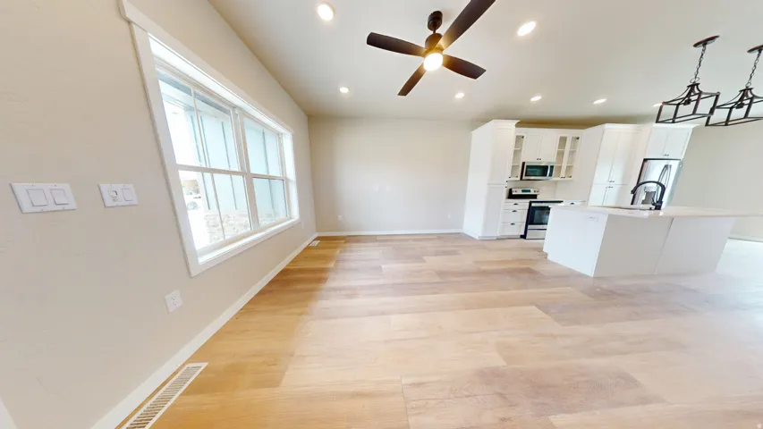 living room featuring glass insert cabinets, white cabinetry, light wood finished floors, appliances with stainless steel finishes, and recessed lighting