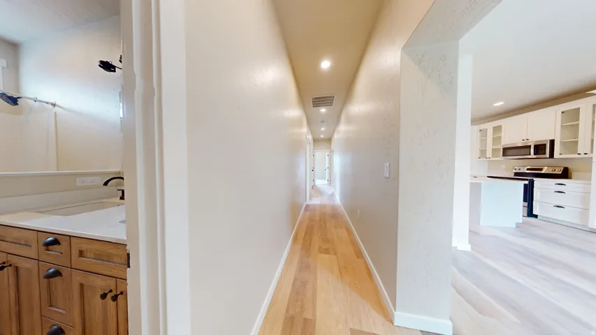Hall featuring light wood finished floors, recessed lighting, and a textured wall