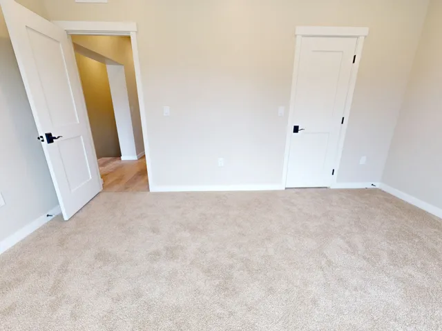 Unfurnished bedroom featuring baseboards and light carpet