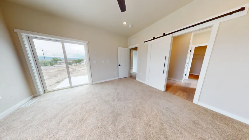 Unfurnished bedroom featuring a barn door, light colored carpet, access to outside, ceiling fan, and recessed lighting
