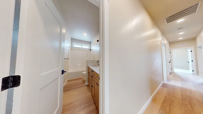 Hall with light wood-style flooring and recessed lighting
