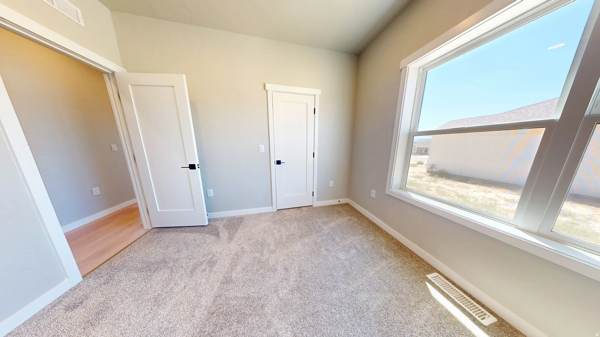 Unfurnished bedroom featuring light colored carpet and baseboards