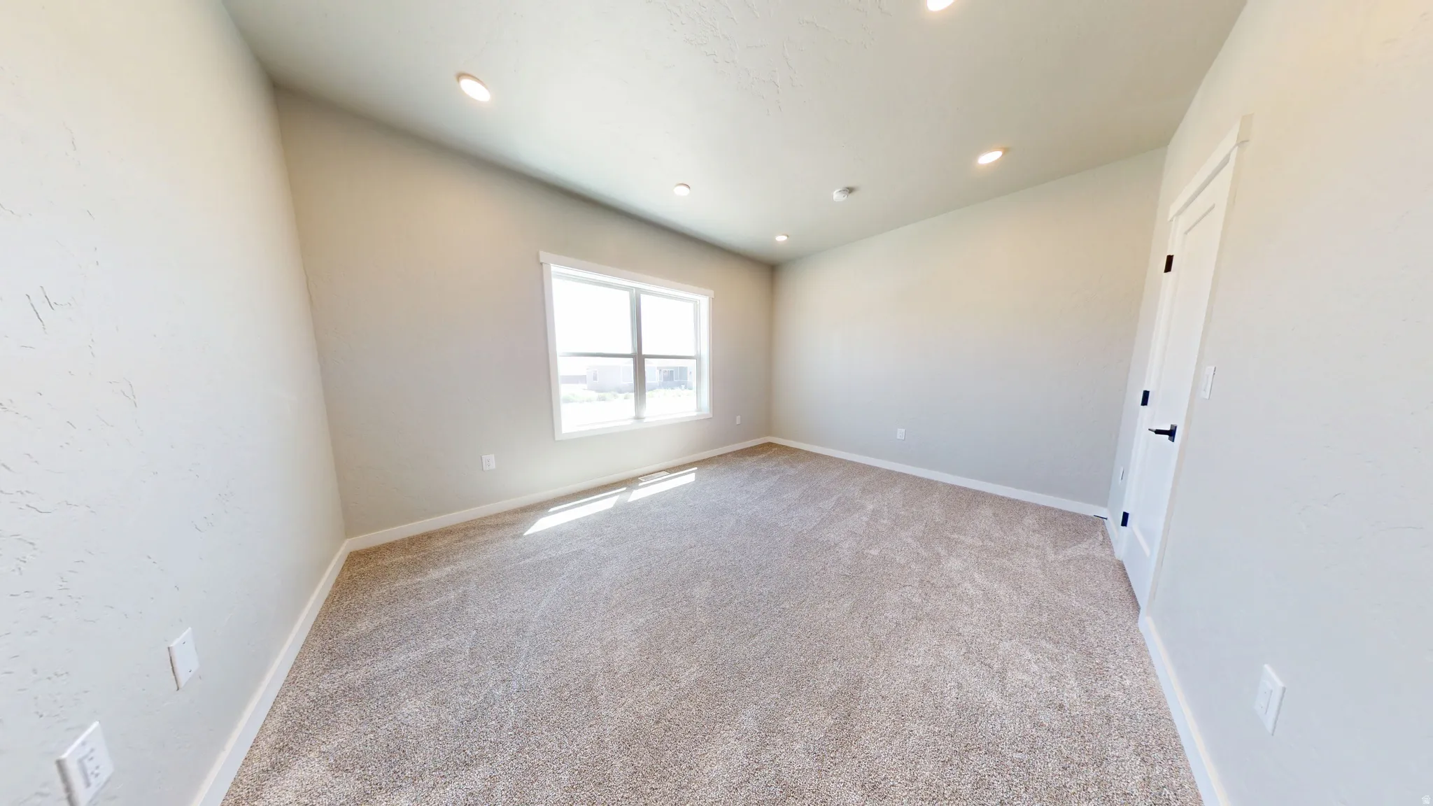 Empty room with light colored carpet and recessed lighting