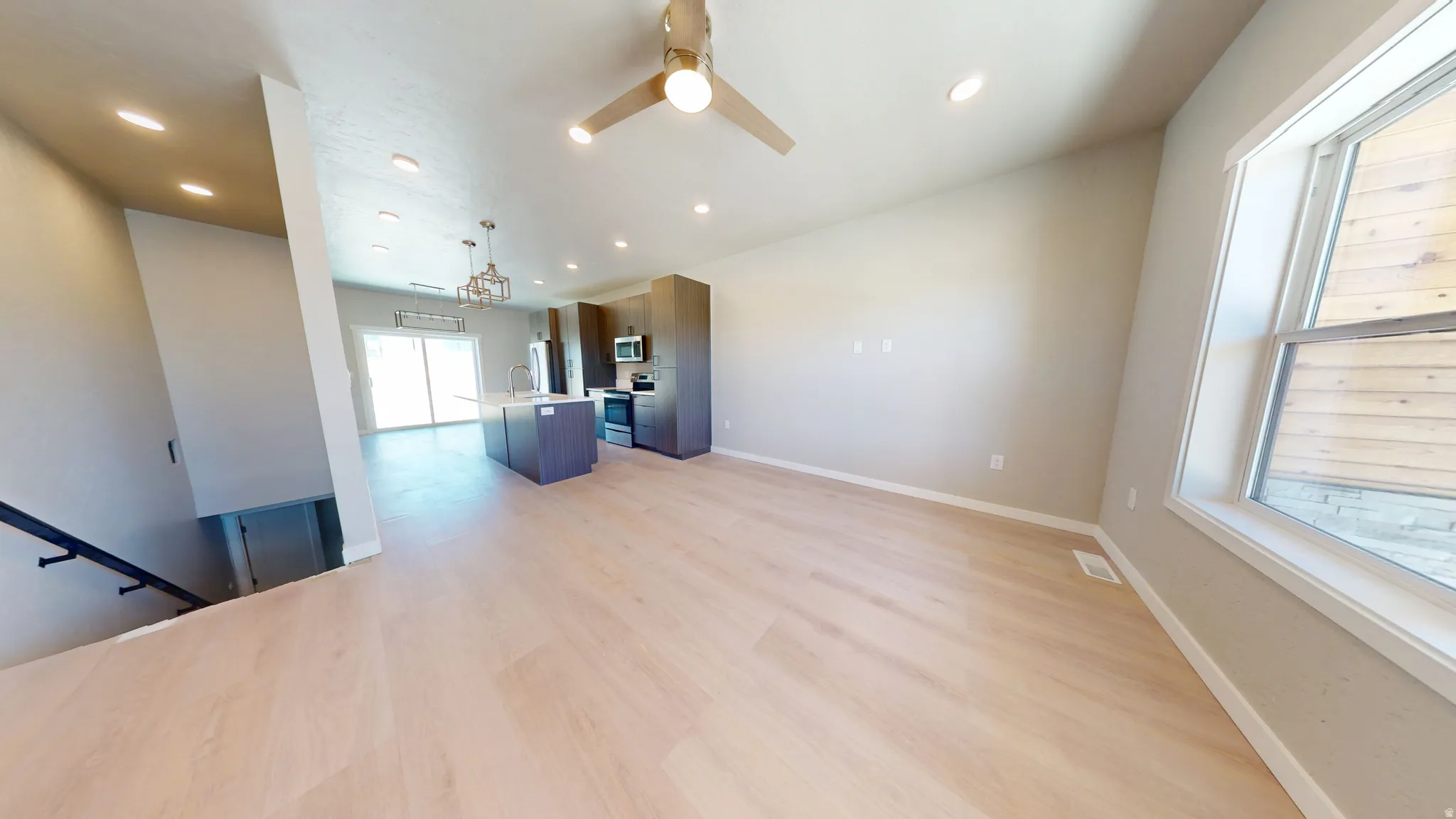 Unfurnished living room with light wood finished floors, a ceiling fan, and recessed lighting