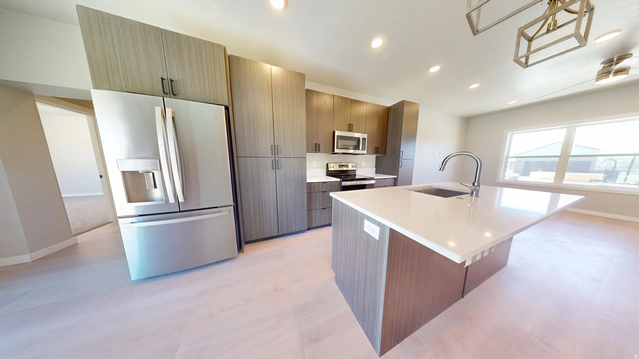 Kitchen with appliances with stainless steel finishes, a kitchen island with sink, recessed lighting, modern cabinets, and light stone counters