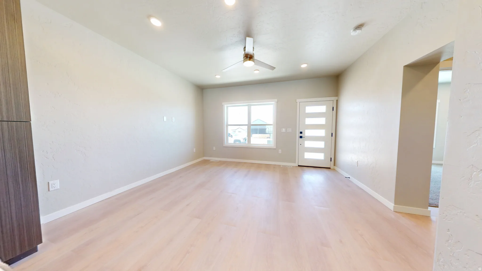 Unfurnished room with light wood-style floors, ceiling fan, a textured wall, and recessed lighting