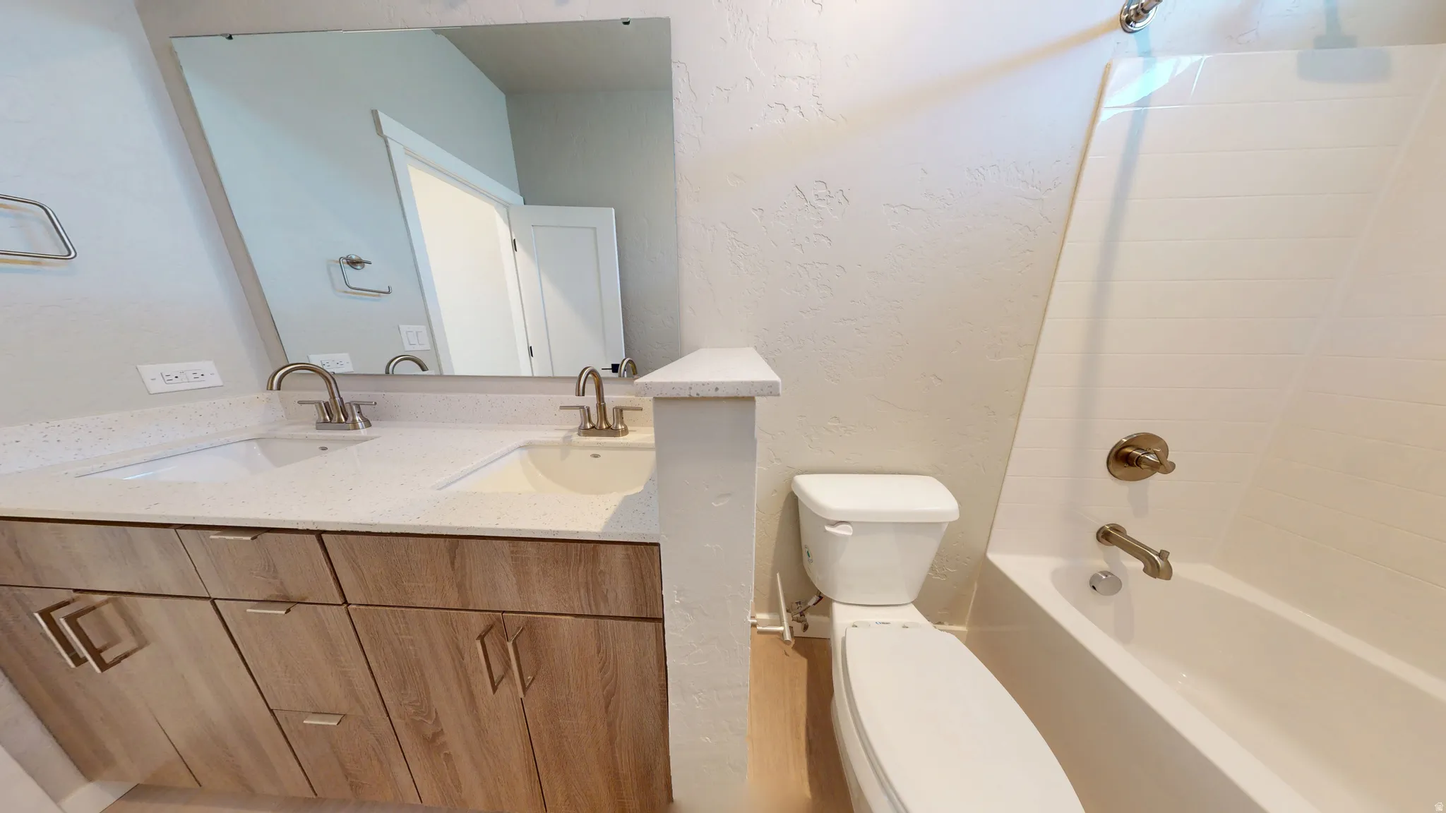 Full bath featuring a textured wall, double vanity, and tub / shower combination