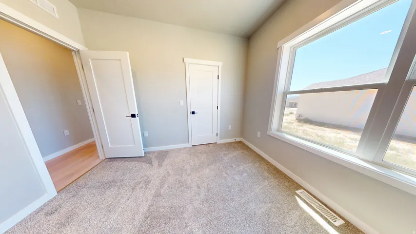 Unfurnished bedroom featuring light colored carpet and baseboards