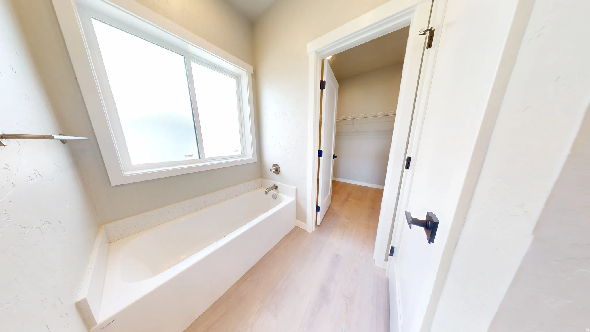 Bathroom with light wood-type flooring, a bath, and a walk in closet