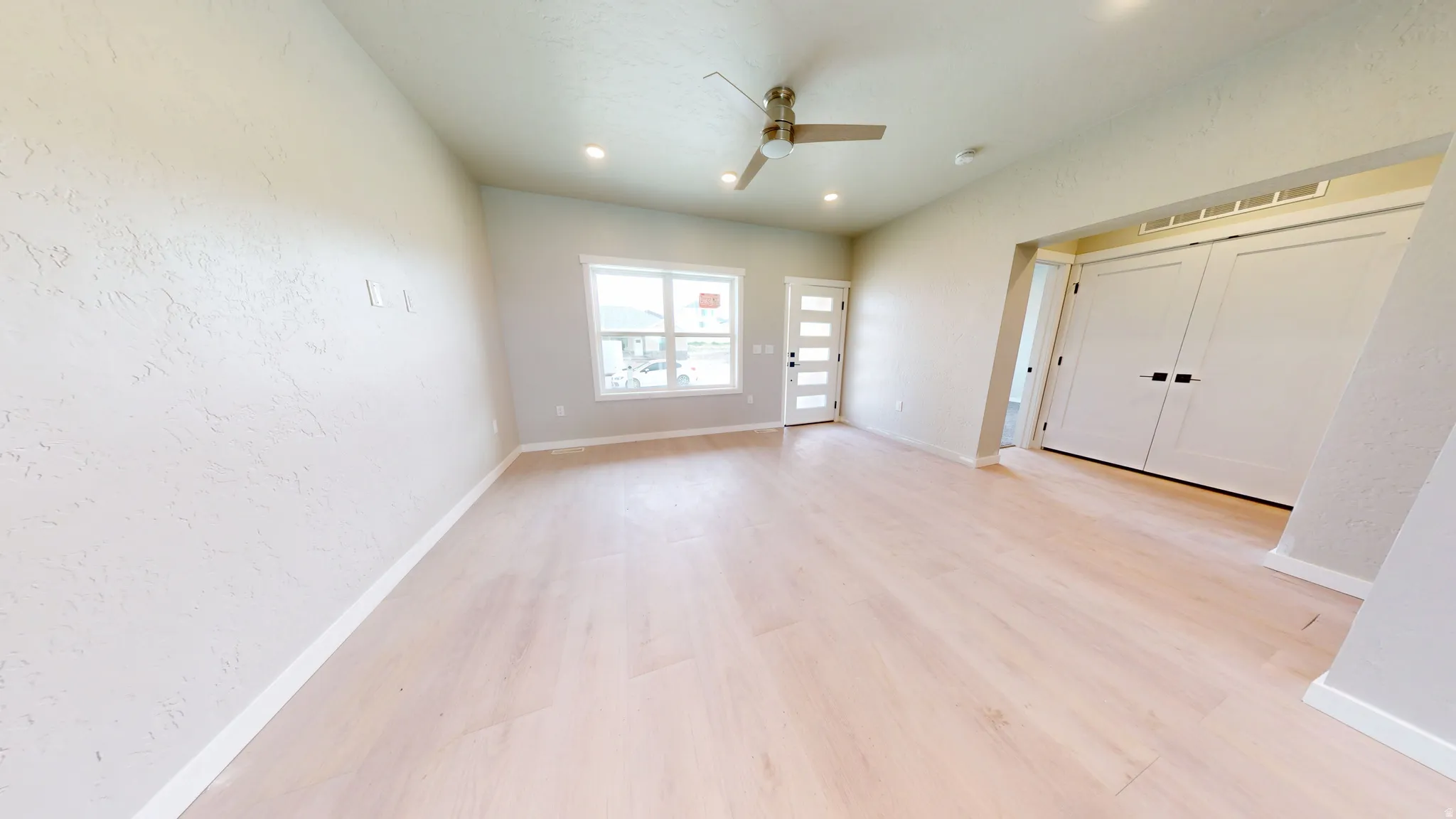 Spare room with a textured wall, light wood-style flooring, ceiling fan, and recessed lighting