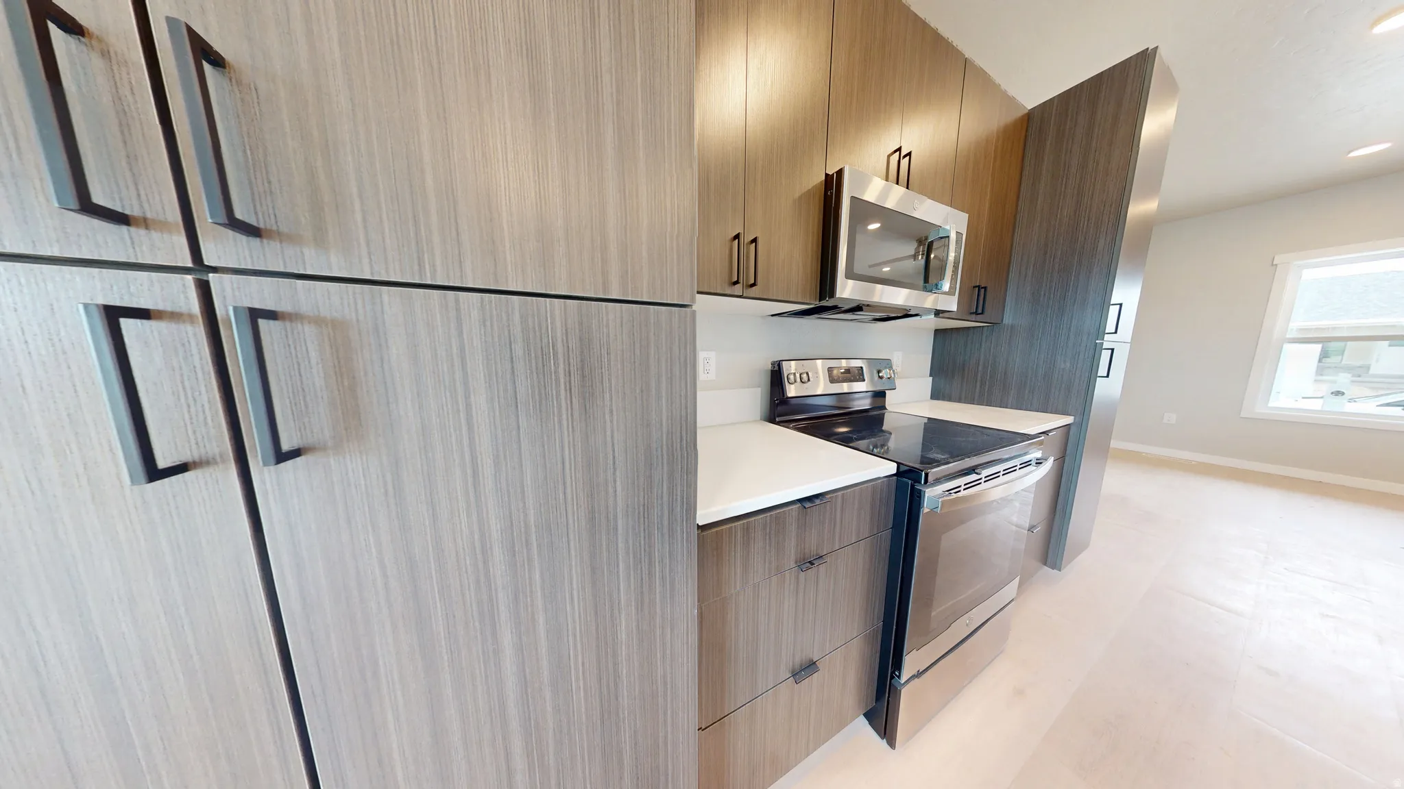 Kitchen with stainless steel appliances, modern cabinets, light countertops, and recessed lighting