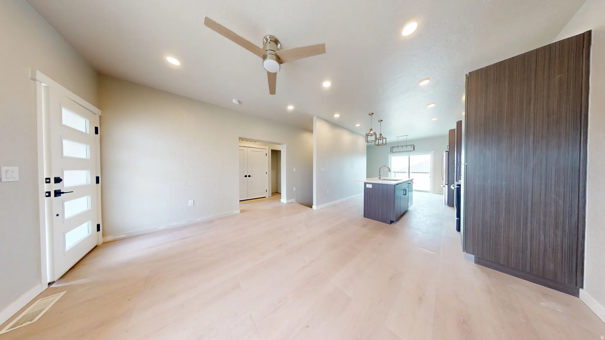 Unfurnished living room with recessed lighting, a ceiling fan, light wood-style floors, and a chandelier