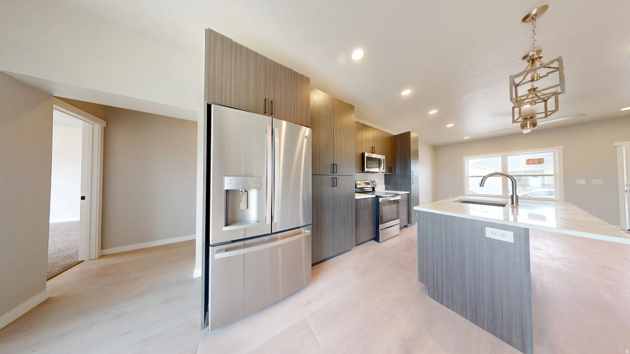 Kitchen with appliances with stainless steel finishes, modern cabinets, a kitchen island with sink, recessed lighting, and hanging light fixtures