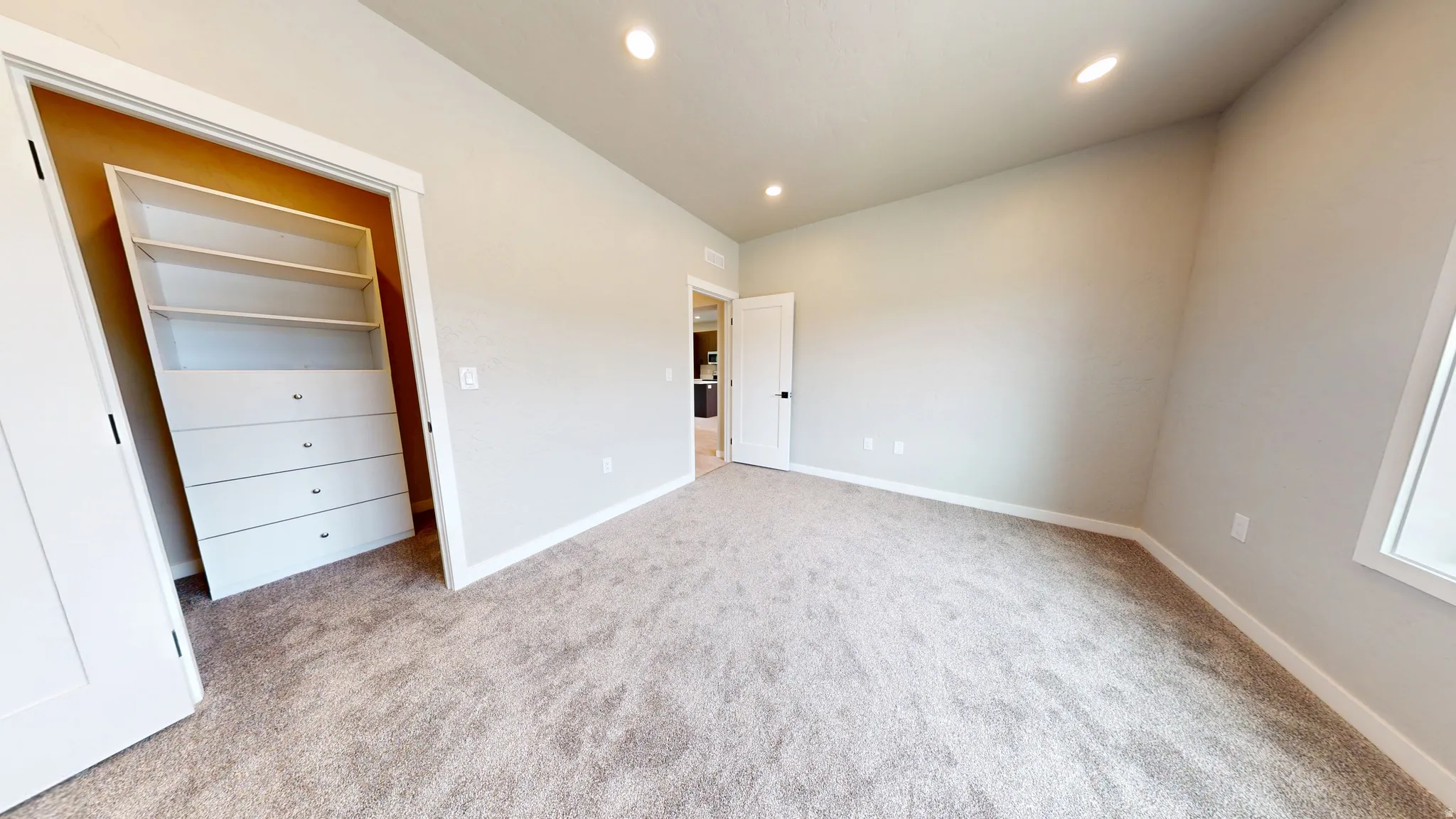 Unfurnished bedroom with recessed lighting, light carpet, and a walk in closet