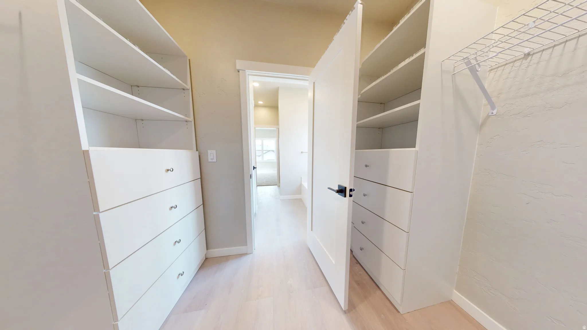 Walk in closet with light wood-style floors