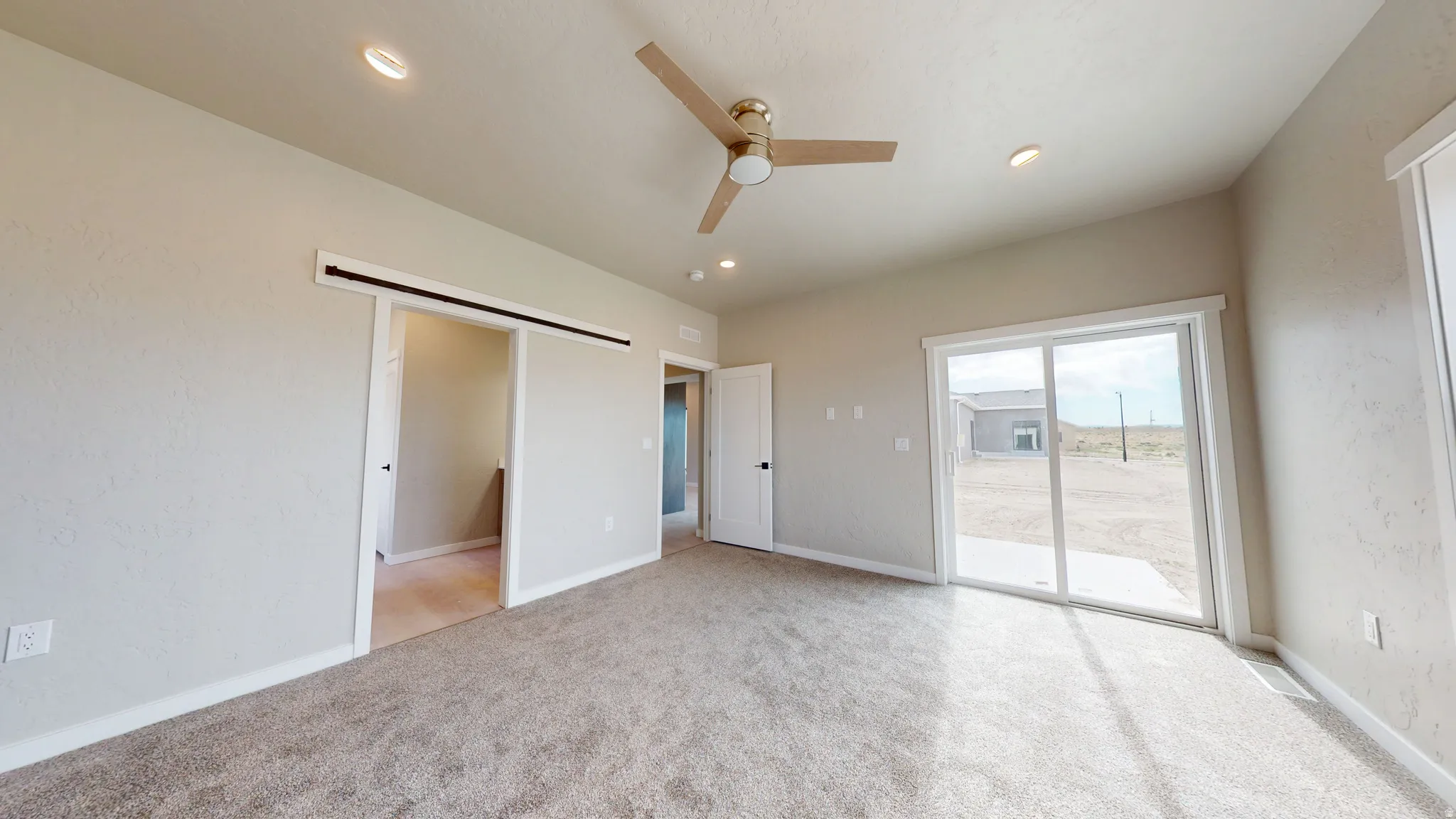 Unfurnished bedroom featuring access to exterior, a barn door, light colored carpet, a ceiling fan, and recessed lighting