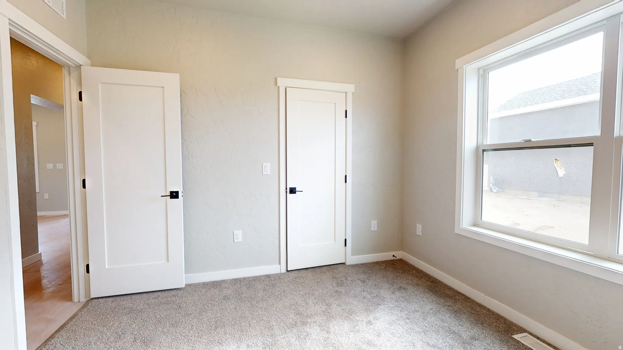 Unfurnished bedroom with light colored carpet and baseboards