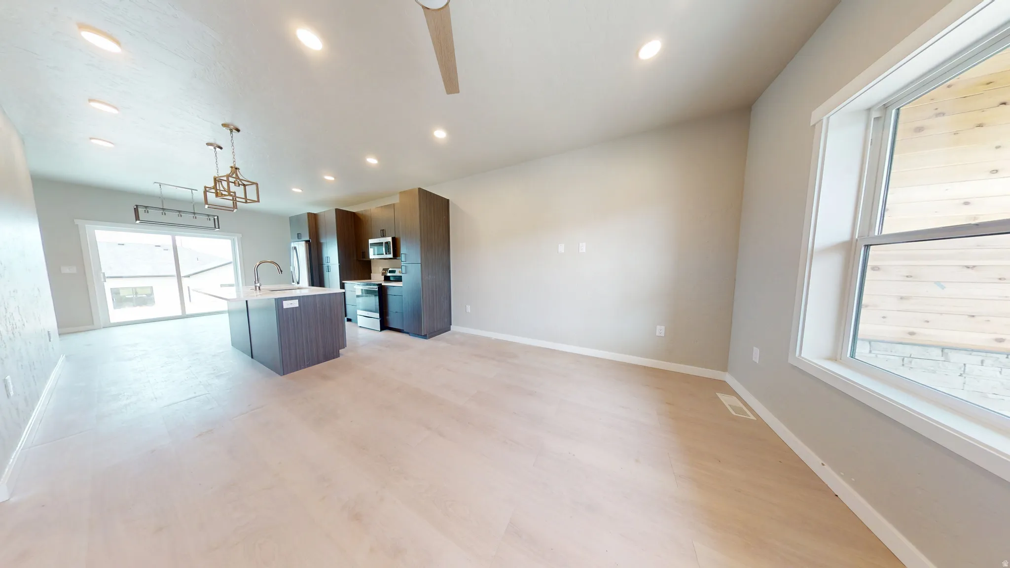 Kitchen featuring an island with sink, open floor plan, modern cabinets, recessed lighting, and stainless steel appliances