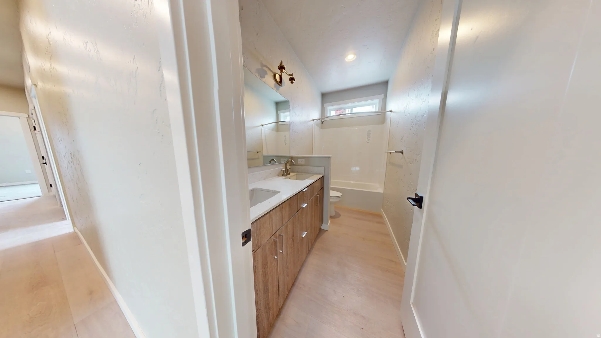 Full bathroom with double vanity and light wood-style floors