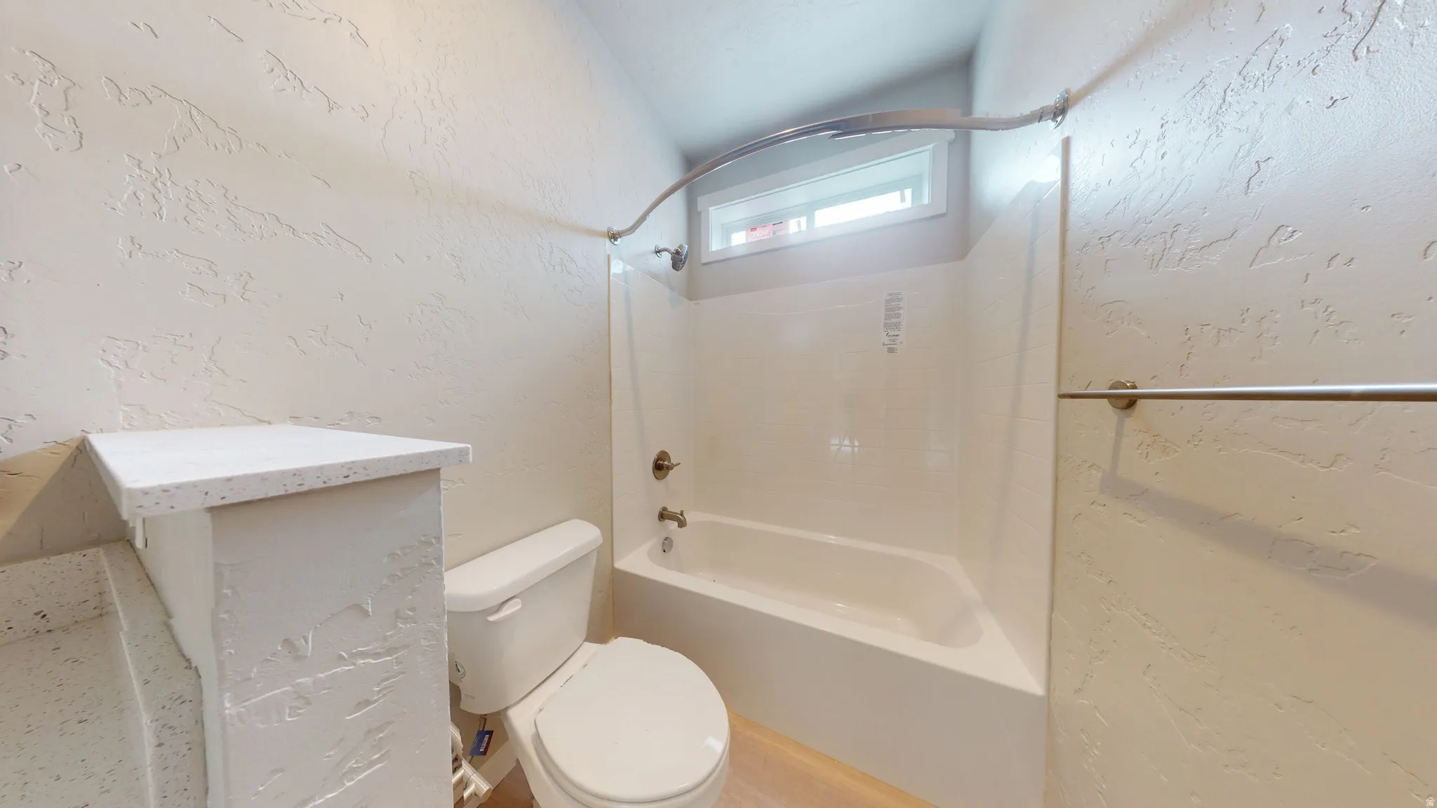 Full bathroom with a textured wall and washtub / shower combination