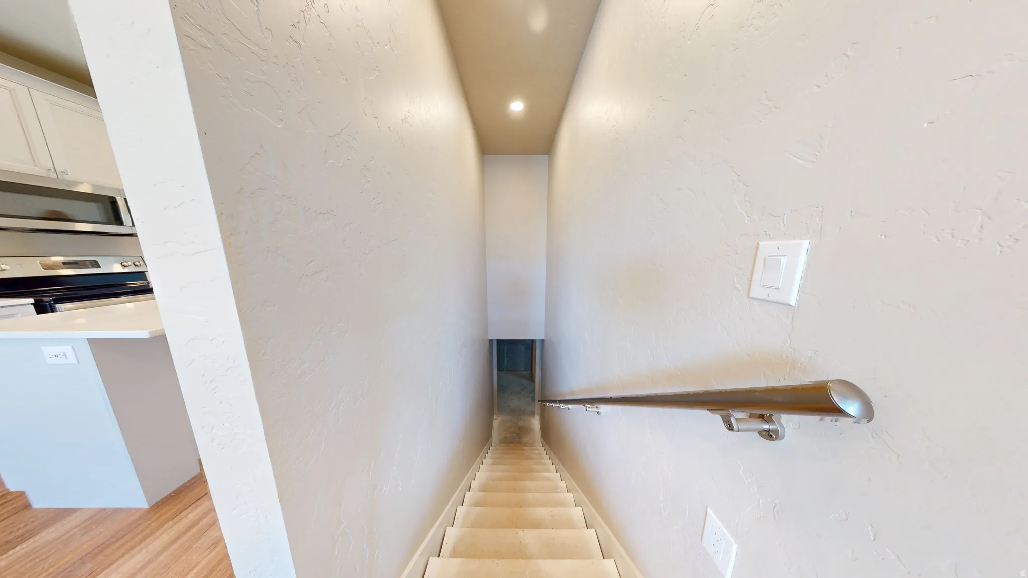 Stairway featuring a textured wall and recessed lighting