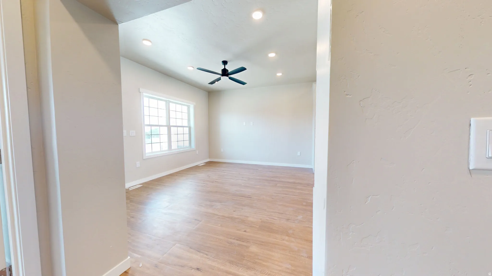 Unfurnished room featuring light wood-type flooring, recessed lighting, ceiling fan, and a textured wall