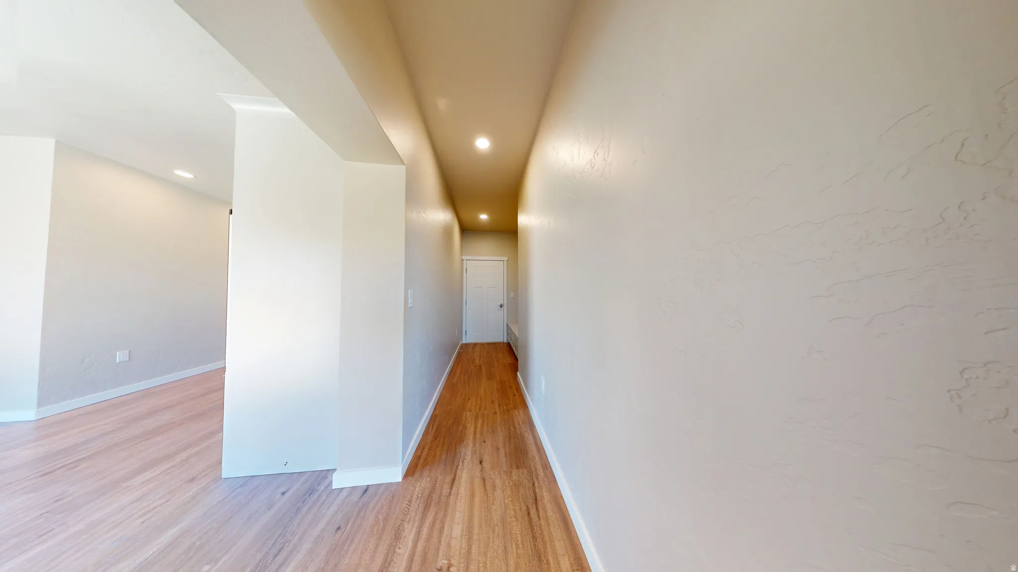 Hall with light wood-type flooring and recessed lighting