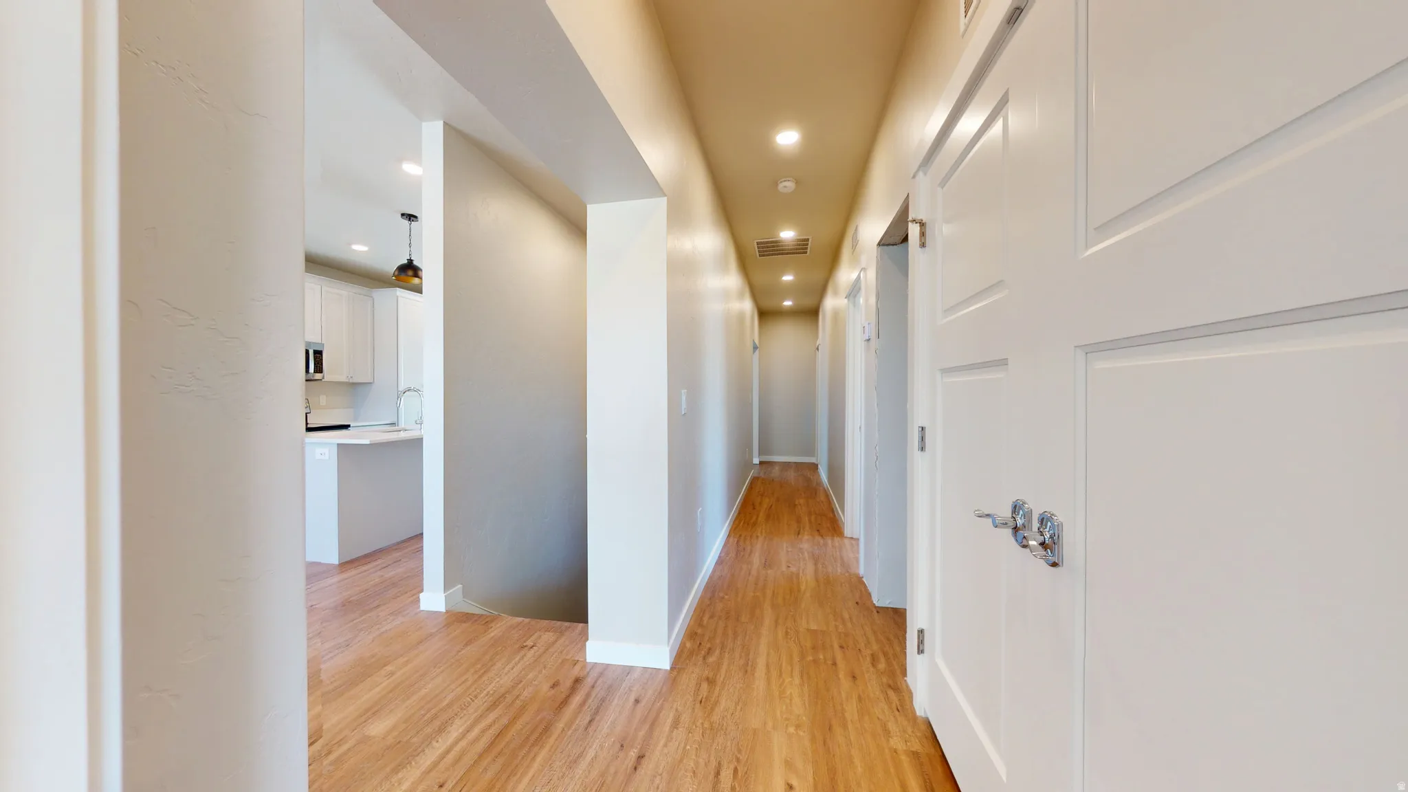 Hallway with light wood finished floors and recessed lighting