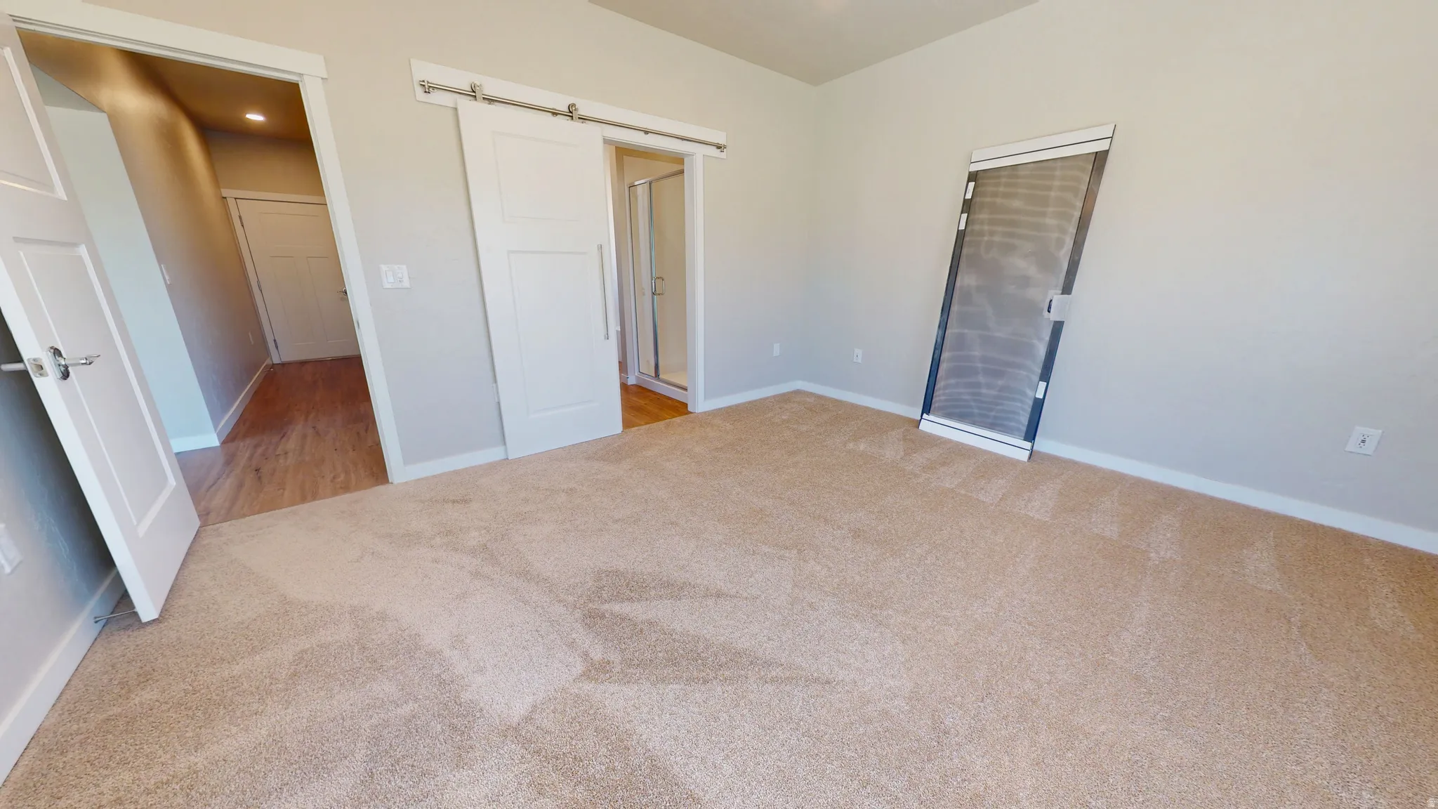 Unfurnished bedroom with a barn door, light carpet, and recessed lighting