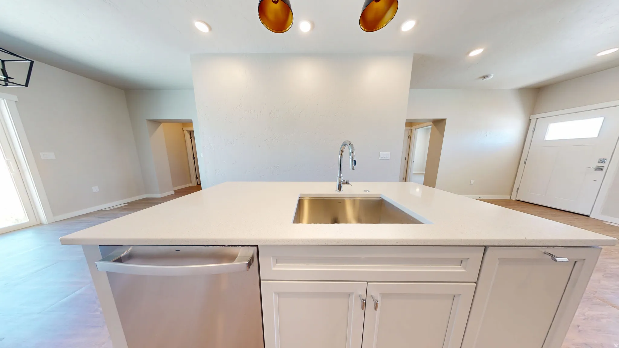 Kitchen with stainless steel dishwasher, a kitchen island with sink, recessed lighting, white cabinets, and light stone counters